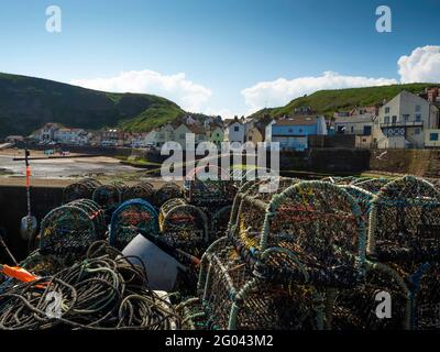 Staithes North Yorkshire Strand und Strandpromenade über die Bucht Ein heller, sonniger Tag mit Krabbenfischern, in denen sich die Töpfe stapeln Der Vordergrund Stockfoto