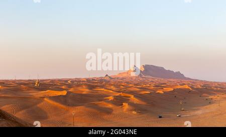 Panorama des Sonnenuntergangs über dem Bergrücken des Fossil Rock und den goldenen Wüstendünen, Sharjah, Vereinigte Arabische Emirate. Stockfoto