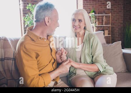 Foto von glücklichen liebevollen alten Paar sitzen Sofa Hände halten Harmony Liebe drinnen Haus Wohnung Stockfoto