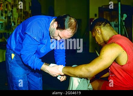 Mike Tyson lässt sich 1986 in Catskill, NY, die Hände von Trainer Kevin Rooney im Fitnessstudio von CUS D'Amato einwickeln. Stockfoto