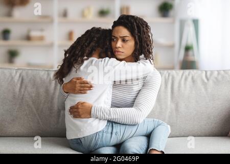 Depressive schwarze Mutter umarmte ihre Tochter und schlosz sie Stockfoto