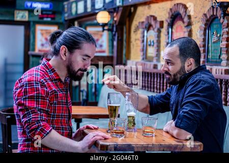 Zwei männliche Freunde trinken gemeinsam Whisky und Bier im Pub. Sie sind betrunken und reden und trösten sich gegenseitig. Stockfoto