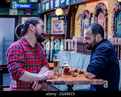 Zwei männliche Freunde trinken gemeinsam Whisky und Bier im Pub. Sie sind betrunken und reden und trösten sich gegenseitig. Stockfoto