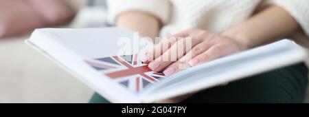 Frau sitzt auf der Couch und hält Notizblock mit Flagge von Großbritannien aus der Nähe Stockfoto