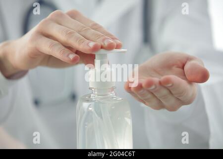 Arzt mit Stethoskop in einer Klinik behandelt seine Hände mit einem Antiseptikum. Nahaufnahme Stockfoto