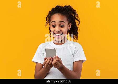 Aufgeregt schwarzes Mädchen mit Handy im Studio Stockfoto