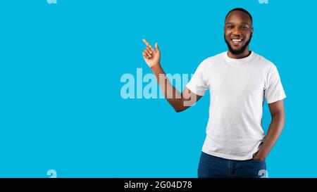 Schwarzer Mann Zeigt Den Finger Zur Seite Und Lächelt Zur Kamera, Blauer Hintergrund Stockfoto