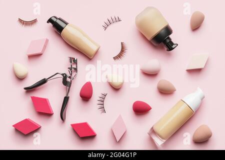 Make-up Schwämme mit tonalem Fundament und Wimpern Lockenstab auf Farbe Hintergrund Stockfoto