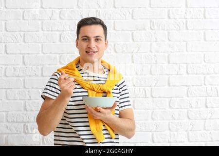 Junger Mann, der auf Backstein Cornflakes isst Stockfoto