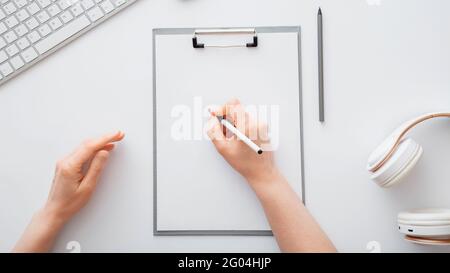 Frau schreibt auf leere Liste im Notizblock, um Liste zu tun. Weibliche Hände zeichnen am Büroarbeitsplatz auf einem Papiertablett. Weibliche Hand schreiben im Notizbuch bei Stockfoto