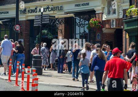 Windsor, Großbritannien. Mai 2021. Die Leute stehen Schlange für den Wetherspoon King and Castle Pub. Windsor war heute voller Einheimischer und Besucher, als der warme Sonnenschein die Menschen zum Bankfeiertag-Montag in die Stadt brachte. Nach der Lifitierung der meisten Covid-19-Beschränkungen boomte die Stadt heute mit Menschen, die draußen essen, auf Flussfahrten gehen und Zeit mit ihren Familien und Freunden genießen. Quelle: Maureen McLean/Alamy Live News Stockfoto