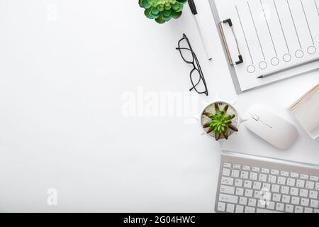 Arbeitsplatz mit Tastatur Maus Brille Papiere grünen Pflanzen. Flach Lay White Schreibtisch Home Office Arbeitsplatz pc-Computer. Weißer Tisch, Büroansicht von oben mit Stockfoto