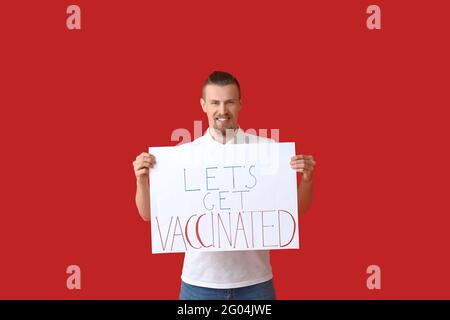 Junger Mann mit Plakat mit Text LET'S IMPFEN lassen Farbiger Hintergrund Stockfoto