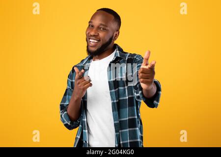 Positiver Schwarzer Bartmann, Der Mit Den Fingern Auf Die Kamera Zeigt, Gelber Hintergrund Stockfoto