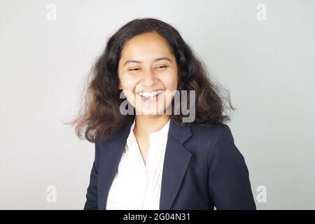 Nahaufnahme einer lächelnden asiatischen Frau, die einen Anzug auf einem weißen Wandhintergrund trägt Stockfoto