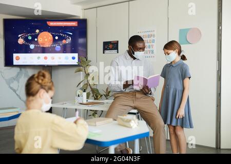 Porträt von Kindern und Lehrern mit Masken im Schulunterricht, covid Sicherheitsmaßnahmen, Kopierraum Stockfoto