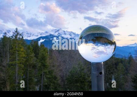 Nahaufnahme einer Kristallkugel mit umgekehrter Spiegelung der umliegenden Bäume und Berge Stockfoto