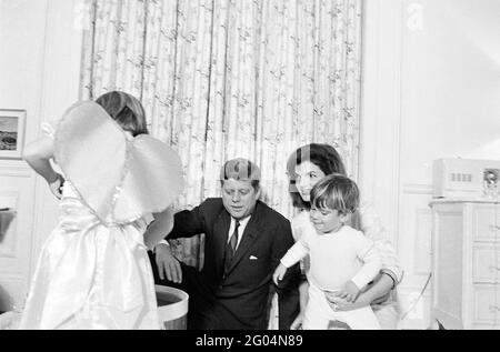 Präsident John F. Kennedy und First Lady Jacqueline Kennedy besuchen mit ihren Kindern Caroline Kennedy und John F. Kennedy, Jr., nach einer gemeinsamen Geburtstagsfeier für die Kinder in Johns Kinderzimmer. White House, Washington, D.C. Stockfoto