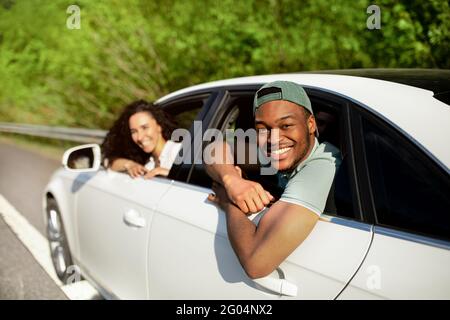 Die besten Freunde, die zusammen mit dem Auto reisen, durch die Fenster schauen, die Kamera anlächeln und im Sommer eine lustige Reise Unternehmen Stockfoto