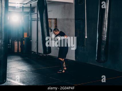Junge Muskel Boxer mit einem Boxsack in der Turnhalle. Boxer schlagen Stanzgeschwindigkeit Tasche Stockfoto