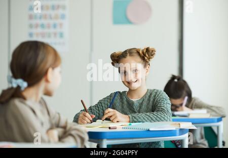 Porträt eines lächelnden Teenagers, das im Klassenzimmer mit einem Freund spricht, Platz kopieren Stockfoto