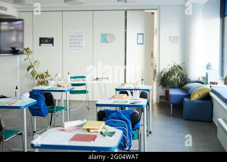 Weitwinkel-Hintergrundbild von Schreibtischen in Reihe mit Lehrbüchern und Verbrauchsmaterialien in der Schule Klassenzimmer Innenraum, Kopierer Platz Stockfoto