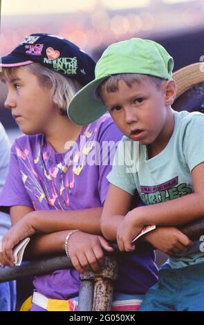 Zwei junge Baseballfans bei einem Spiel, einer trägt ein Ninja Turtles T-Shirt und das Mädchen trägt einen New Kids on the Block Baseballspiel -- Bitte schreiben Sie der Fotografin Kirk Schlea Anerkennung Stockfoto