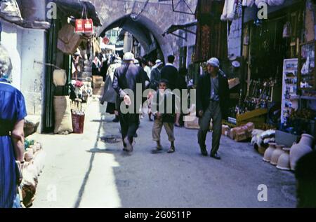 Die Kunden gehen zwischen den Geschäften im alten Teil von A Stadt (Israel 60er Jahre Straßenszene) Stockfoto