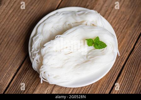 Thailändische Reisnudeln vermicelli auf Teller und Holzhintergrund, Nudeln für Thai-Küche mit einem Gericht Stockfoto