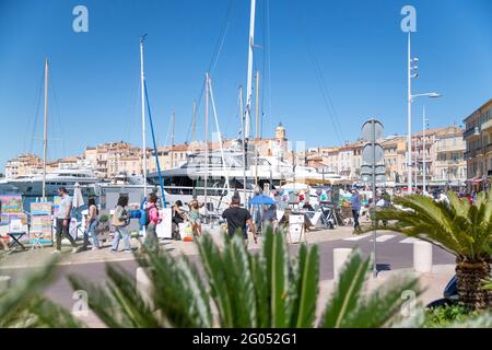 Saint Tropez, Frankreich. Mai 2021. Passanten kommen im Hafen 'Port de Saint Tropez' an Straßenkünstlern vorbei. Quelle: Sebastian Sinterhauf/dpa/Alamy Live News Stockfoto
