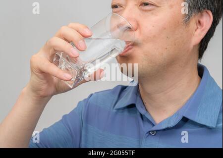 Asiatischer Mann mittleren Alters mit einem Glas Wasser. Stockfoto