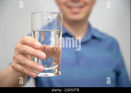 Asiatischer Mann mittleren Alters mit einem Glas Wasser. Stockfoto