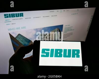 Person, die das Smartphone mit dem Logo des russischen petrochemischen Unternehmens SIBUR Holding PJSC auf dem Bildschirm vor der Website hält. Konzentrieren Sie sich auf die Telefonanzeige. Stockfoto