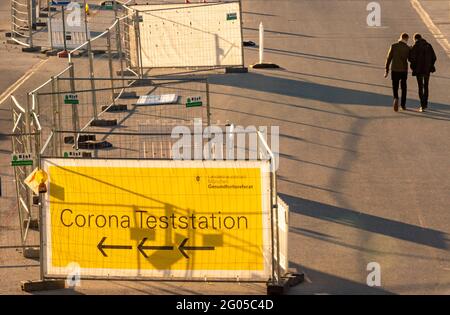 München, Deutschland. Juni 2021. Zwei Personen laufen in den frühen Morgenstunden am Eingang einer noch geschlossenen Corona-Teststation auf der Theresienwiese vorbei. Kredit: Peter Kneffel/dpa/Alamy Live Nachrichten Stockfoto