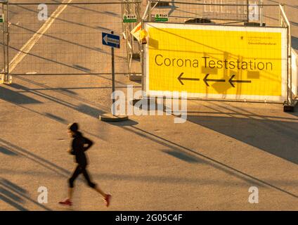 München, Deutschland. Juni 2021. In den frühen Morgenstunden joggt eine Frau am Eingang einer noch geschlossenen Corona-Teststation auf der Theresienwiese vorbei. Kredit: Peter Kneffel/dpa/Alamy Live Nachrichten Stockfoto