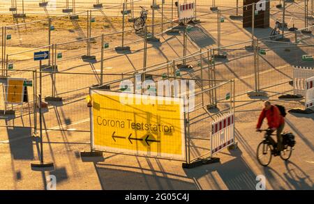 München, Deutschland. Juni 2021. In den frühen Morgenstunden fährt ein Mann mit dem Fahrrad am Eingang einer Corona-Teststation auf der Theresienwiese vorbei, die noch geschlossen ist. Kredit: Peter Kneffel/dpa/Alamy Live Nachrichten Stockfoto