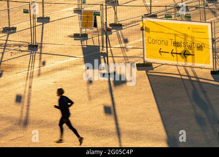 München, Deutschland. Juni 2021. In den frühen Morgenstunden joggt eine Frau am Eingang einer noch geschlossenen Corona-Teststation auf der Theresienwiese vorbei. Kredit: Peter Kneffel/dpa/Alamy Live Nachrichten Stockfoto