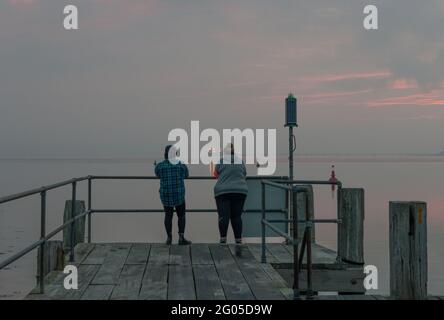 Currabinny, Cork, Irland. Juni 2021. Zwei Frauen waren früh aufgestanden, um die Morgenröte am Currabinny Pier, Co. Cork, Irland, zu beobachten. - Credit; David Creedon / Alamy Live News Stockfoto