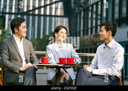 Drei asiatische Geschäftsleute, die in einer Kaffeeaufnahme über Geschäfte im Freien diskutieren Stockfoto