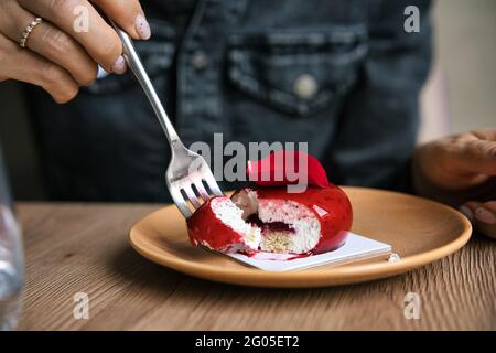 Französischer Mousse-Kuchen mit roter Glasur auf Holzgrund bedeckt. Modernes europäisches Kuchengebäck. Geringer Fokus Stockfoto