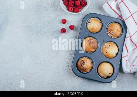 Gebackene Himbeer-Muffins auf einem Kühlgestell auf blauem Beton-Tischhintergrund. Draufsicht, Kopierbereich. Stockfoto