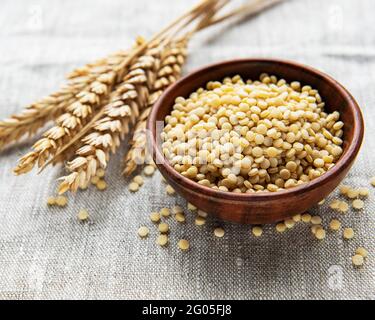 Roher Couscous in einer Holzschale auf dem Tisch Stockfoto