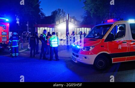 Hamburg, Deutschland. Mai 2021. Vor der U-Bahn-Station am Bahnhof Hagendeel stehen Rettungsfahrzeuge mit blauem Licht neben Feuerwehrleuten, aus denen dichter Rauch austicht. Aufgrund des starken Rauchs nach einem Brand in einem U-Bahn-Tunnel wurden 55 Personen aus zwei Zügen in Sicherheit gebracht. Mehrere Eisenbahnsabler branden, teilte die Feuerwehr mit. Quelle: Jonas Walzberg/dpa/Alamy Live News Stockfoto