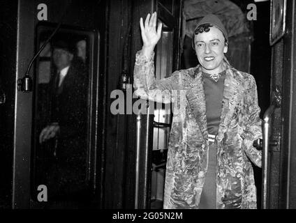 Besteigen Sie den Bootszug „RMS Queen Mary“ für ihren ersten Besuch in Amerika, der englischen Schriftstellerin und Dramatikerin Dodie Smith (1896 - 1990), die ihren charakteristischen Pelzmantel in Waterloo Station, London, am 27. Oktober 1937 trug. Dorothy Gladys „Dodie“ Smith. Autor der einhundert Dalmatiner. Pelz Mode Großbritannien 1930er Jahre 1937 Frauen Dame Damen Autor Schriftsteller Kuss curl Kuss Locken trendige Mode extravagant Kommode Dressing Frau Schauspielerin Dame winken fangen Zug verlassen Stockfoto