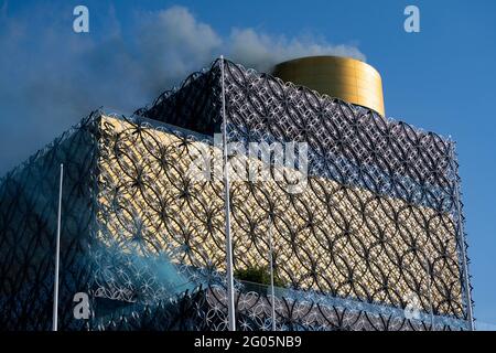 Rauch wird aus der Birmingham Library freigesetzt, um Stickoxide darzustellen, die durch die heute in Birmingham gestartete Reinluftzone eingespart wurden. Die Birmingham Clean Air Zone (CAZ) erhebt für die Einfahrt in das Herz von Birmingham Gebühren für stark verschmutzende Fahrzeuge, einschließlich Autos. Im Rahmen des Programms werden Autos, Taxis und Lieferwagen eine tägliche Gebühr von £8 zahlen müssen – wobei Überwachungskameras täglich rund um die Uhr in Betrieb sind. Bilddatum: Dienstag, 1. Juni 2021. Stockfoto