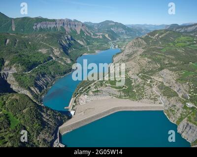 LUFTAUFNAHME. Der Damm des Serre-Ponçon-Sees mit dem EDF-Kanal und dem Fluss Durance in der Ferne. Frankreich. Stockfoto