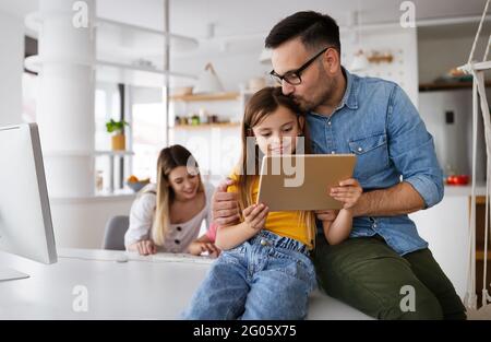 Eltern helfen Kindern, die online zu Hause studieren. Lockdown und Online-Schule, Technologie-Konzept. Stockfoto