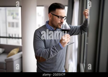 Glücklicher junger Geschäftsmann im Büro mit Blick aus dem Fenster Stockfoto