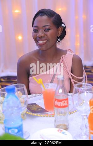 KAMPALA, UGANDA - 08. Mai 2021: Die schöne afroamerikanische Dame, die bei der Hochzeitsfeier gut gekleidet war, hat ein paar Drinks und Spaß und trägt riesige S Stockfoto