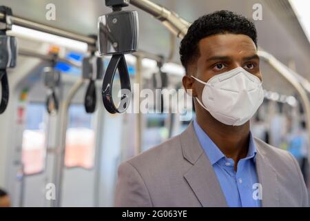 Afrikanischer Geschäftsmann im Zug trägt Gesichtsmaske Stockfoto